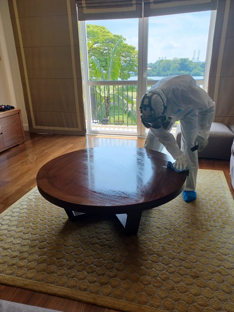 the guy is deep cleaning the wooden table in the living room